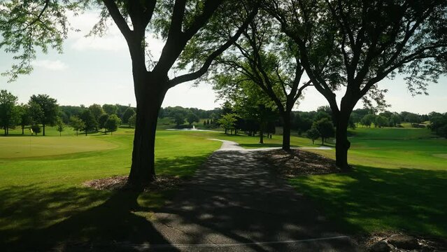 walking down a cart path shaded by surrounded trees on a golf course at a country club