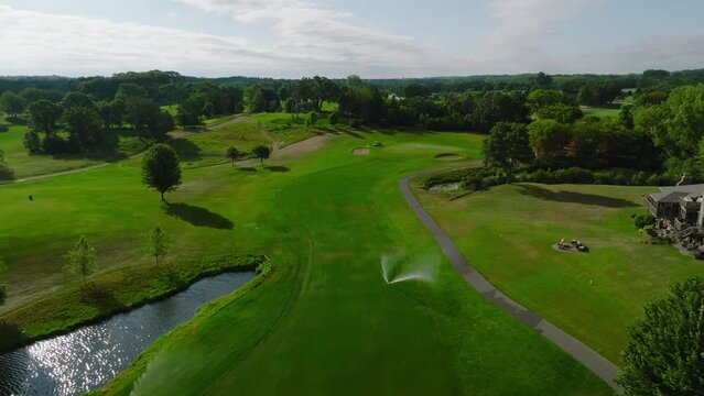 aerial drone shot of a golf hole with fairway bunkers at a country club with sprinklers running