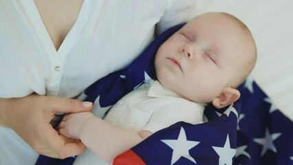 Top view of the mother holding her newborn child wrapped him in the usa flag while he sleeping. Newborn baby and patriotism concept - Powered by Adobe