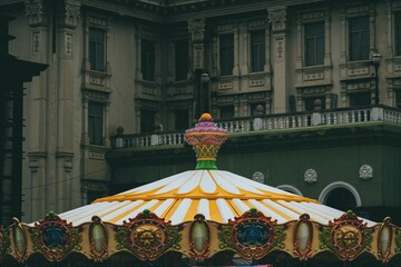 Colorful carousel ride against a gray and green building