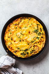 Traditional Spanish potato tortilla or omelette in black pan.
