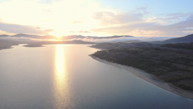 aerial drone shot of sunset on the big lake. reflection of the sky and twilight on the beach. nature stock videos 4K. hilly background. ebro reservoir in Cantabria, Spain.