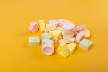 Scattered tablet candies on yellow background. Compressed sugar powder confectionery, dextrose...