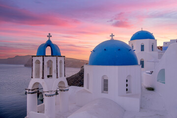 Breathtaking sunset over the famous Santorini blue domes churches in Oia, Santorini Greece. The...