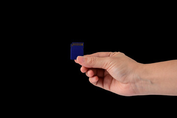 Hand and SD memory card isolated on black background