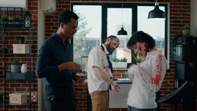 Hungry creepy zombie talking with businessman while dead coworker covered in blood walks by. Person discussing with bizarre looking evil undead monster in office while mindless colleague passes by.