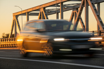 Blured car driving over a bridge at sunset