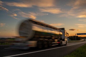 Blured  tanker truck driving along a highway at sunset