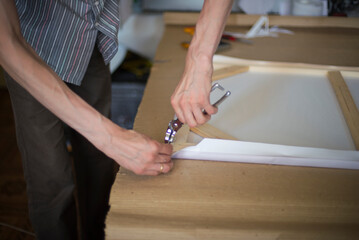 close up of a person hands stretching the canvas on the stretcher