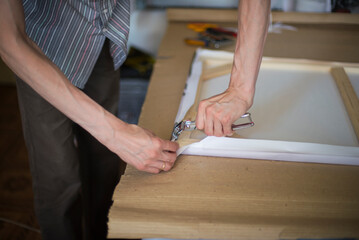 close up of a person hands stretching the canvas on the stretcher