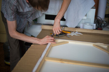 close up of a person hands stretching the canvas on the stretcher