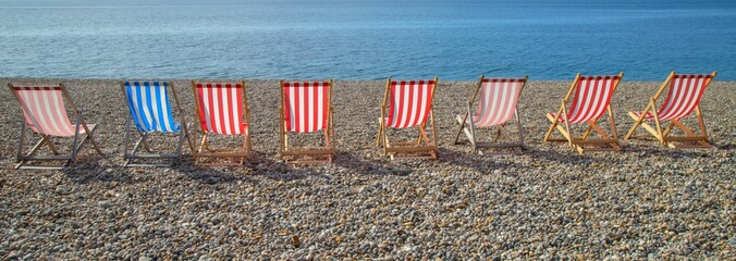 Panoramic shot of red and blue deckchairs by the beach