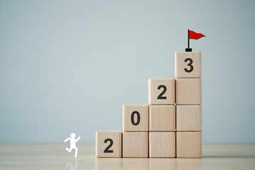 2023 new year challenge goal and target, Achievement and business success. Rises up stairs to target. Human improvement. Personal growth. Human icon looking for 2023 on ladder up to goal flag. © tanoy1412
