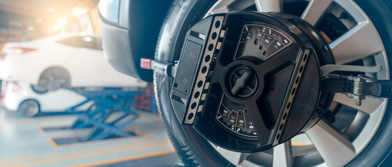 Wheel alignment equipment grip the tire of car wheel in car repair shop. Auto wheel alignment in...