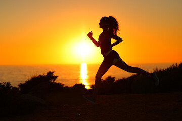 Silhouette of a runner running at sunset on the beach