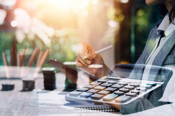 Woman accountant use calculator and computer with holding pen on