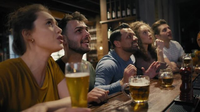 Group of friends cheering to soccer match in the pub. Shot with RED helium camera in 8K. 