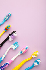 Colorful toothbrushes on purple background. Vertical photo