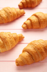 Freshly baked croissants on pink wooden background Warm Fresh Buttery Croissants and Rolls. French and American Croissants and Baked Pastries