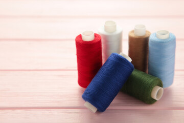 Color sewing threads on wooden pink background