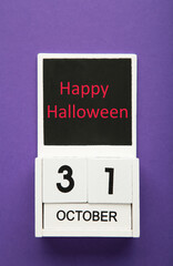Wooden calendar with the date of October 31 on a violet background. Happy Halloween