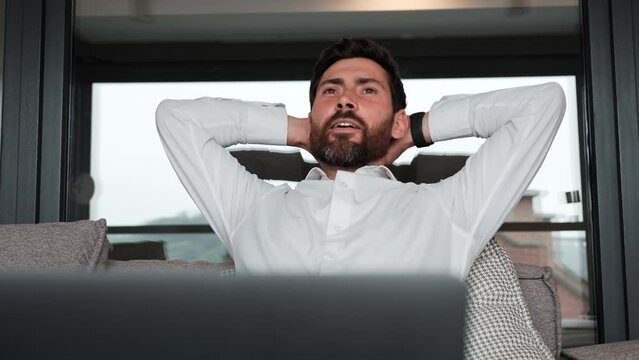 Businessman finishing working in luxury apartment. Bearded handsome business man worker relax sit at couch finished laptop work put hands behind head feel satisfied with work well done stress relief.