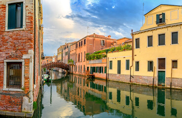 View on the narrow cozy streets of the canals with parked boats in Venice, Italy. Architecture and landmark of Venice.