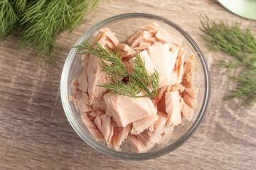 canned tuna in a clear glass cup on wooden background