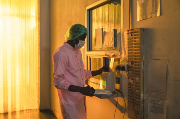 African quality control employee man in sterile suit clock in with time clock system of factory...