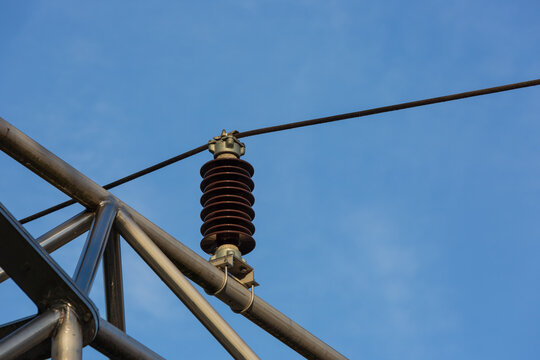 Close up of brown power line isolator on blue sky