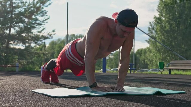 Athlete excercising push ups on sports ground