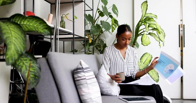Young businesswoman sitting on couch looking through papers