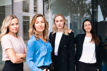 Confident businesswomen standing together outside glass wall