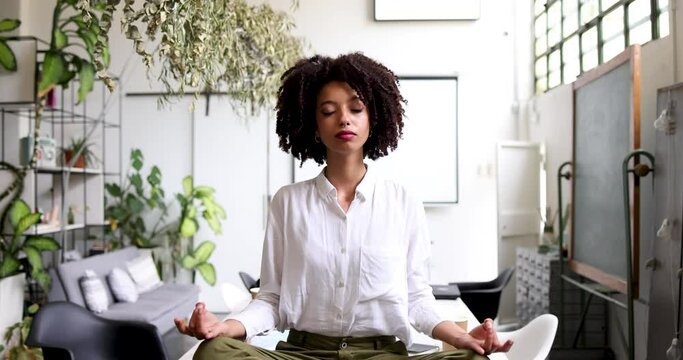 Young businesswoman meditating cross-legged on office table
