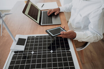 Engineer using laptop sitting with green technology at desk in office