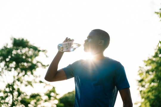 Young man drinking water from bottle on sunny day