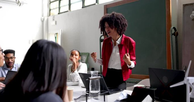 Young businesswoman holding motivational speech in front of colleagues
