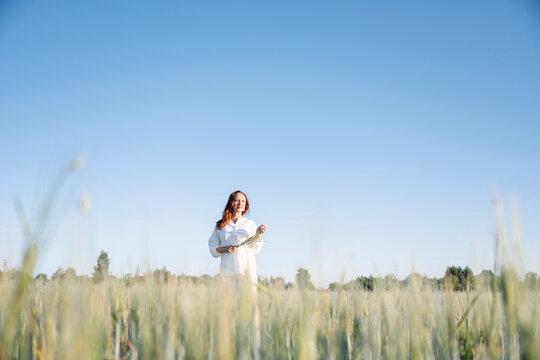 Woman standing amidst cornfield under blue sky