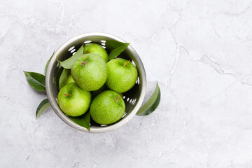 Fresh green apples in colander on stone table