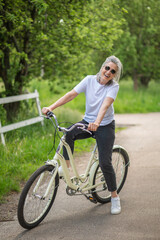 A woman in sportswear with a bike in the park feeling cheerful