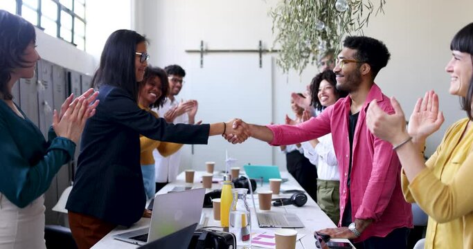 Two businesswomen and man shaking hands in office meeting