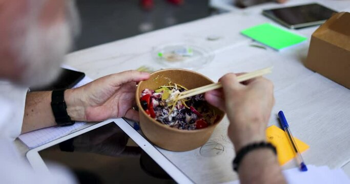 Hands of businessman eating luch with chopsticks