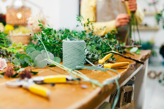 Gardening tools by leaves on workbench at flower shop