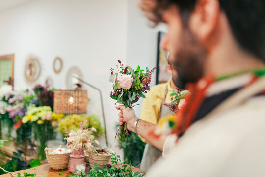 Florist holding bouquet standing with colleague at floral shop