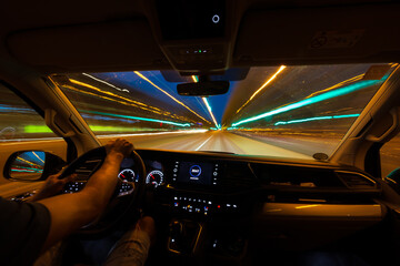Interior view of a person driving a car with long exposure light trails.