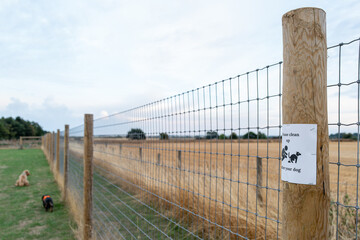 Shallow focus of a generic Dog Poo Pick sign seen attached to a post at a dog agility field. A...