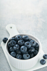 Blueberry. White bowl of fresh blueberries on grey stone background table. Tasty ripe blueberries. Place for text. Food background. Top view.