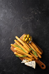 Meat, cheese and snackes plate, board and grissini on black background