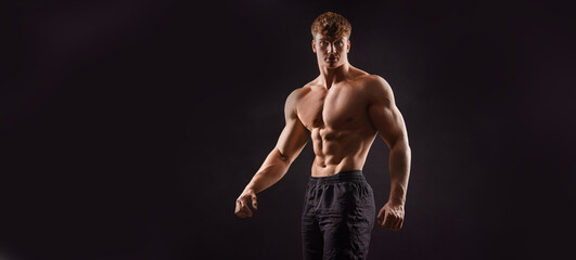 Fototapeta na wymiar The torso of attractive muscular male body builder on black background.