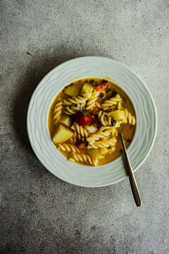 Overhead view of a bowl of homemade pasta, potato, tomato and vegetable soup
